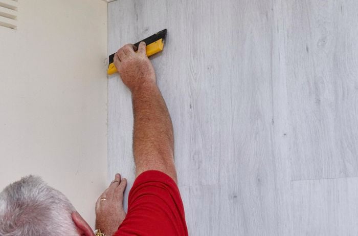 Faux wooden panels being pressed firmly into place on a feature wall