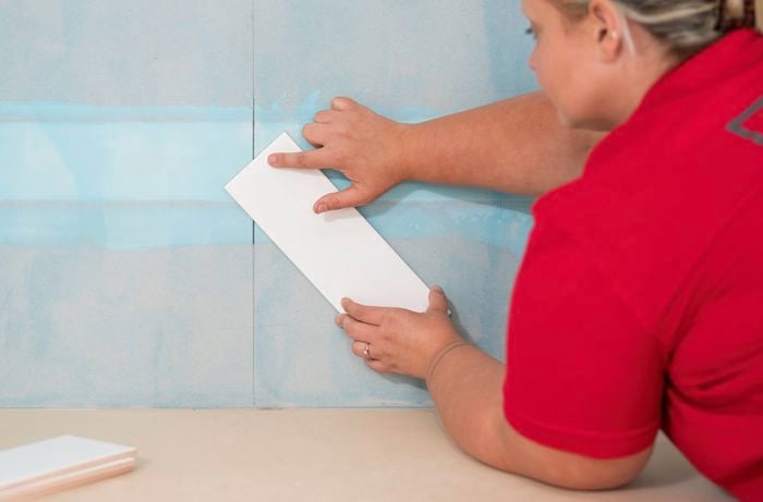 A Bunnings Team Member is finding the centre of the tile to ensure the herringbone pattern is symmetrical.