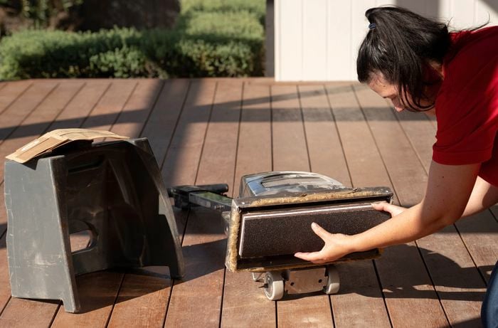 A person is preparing a drum sander by fitting the sanding belt correctly before sanding old timber decking. 
