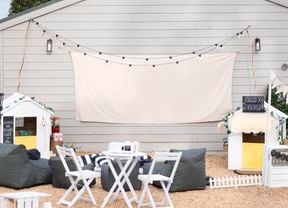 Outdoor furniture in front of a wall with canvas screen and fairy lights