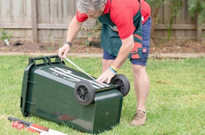 Bunnings team member masking up a wheelie bin