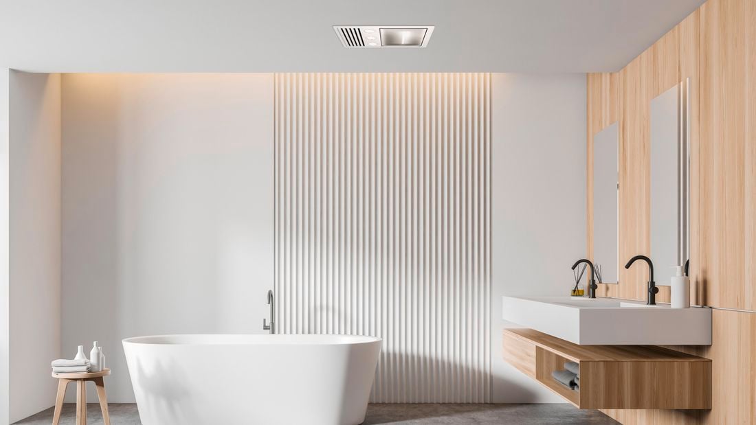Freestanding bath, stool with towels on it and a basin and cabinet in a bathroom