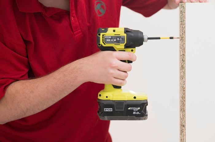 A Bunnings Team Member is using a power drill to screw  the bottom panel to the back panel. 
