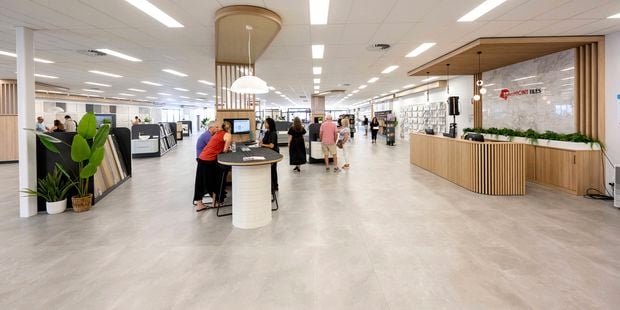 Wide view of a spacious tile showroom with customer service areas, product displays, and people exploring the space