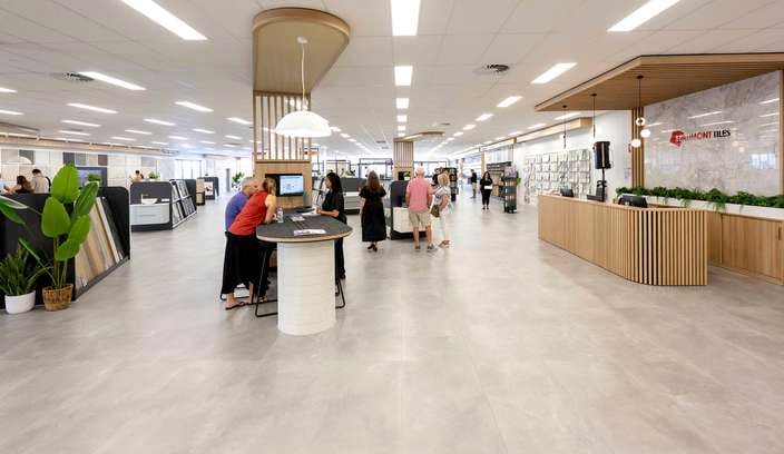 Wide view of a spacious tile showroom with customer service areas, product displays, and people exploring the space