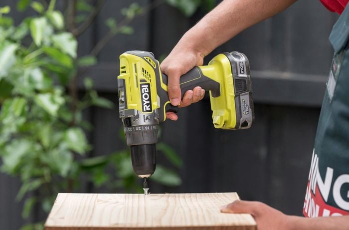 A Bunnings Team Member using a cordless drill on a piece of wood