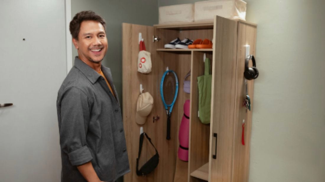 A man standing in front of a cupboard, with exercise equipment stored using Command wall hooks