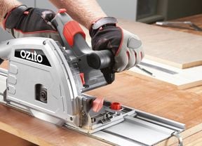 A person using an Ozito circular saw to cut a MDF board.