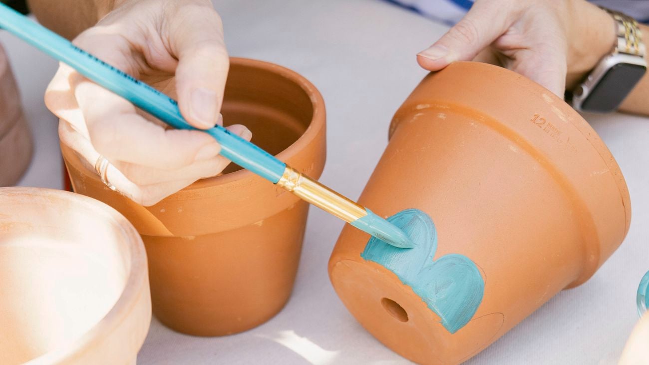 A person painting terracotta pots.