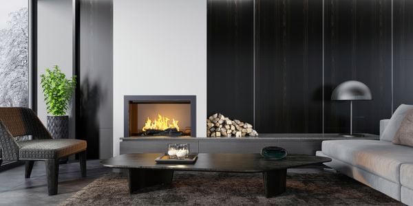 Modern living area with couch, coffee table, kindling and fireplace.