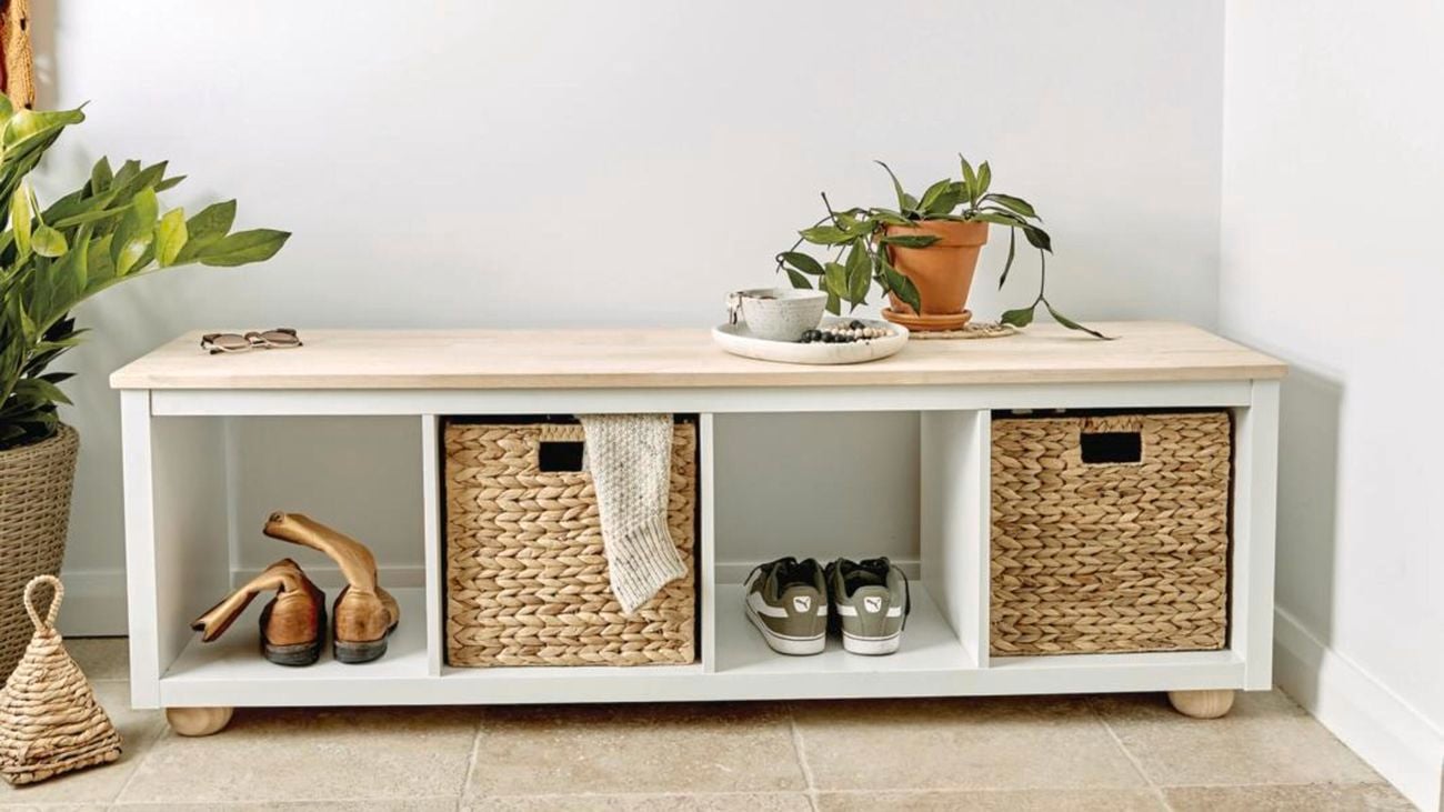 A hallway bench storage solution with baskets, shoes and potted plants.