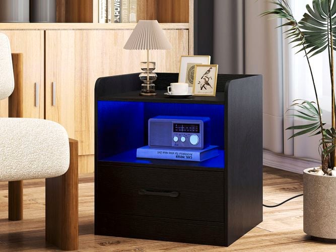 A black bedside table with a lamp and picture frames on it.