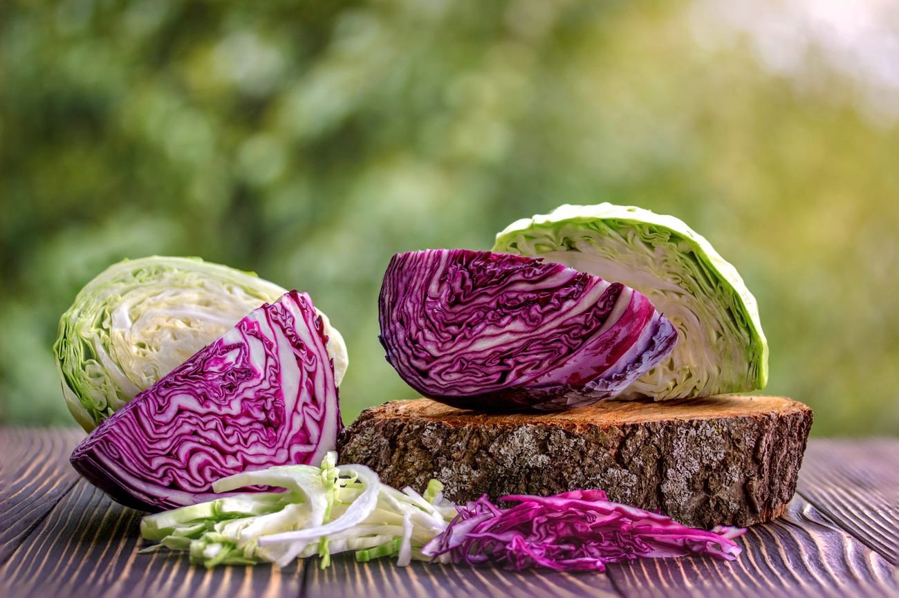 Cut red and white cabbages on a wooden table