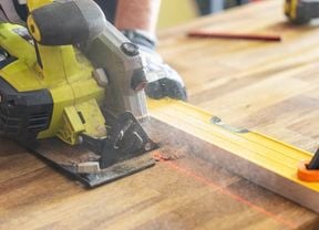 Close up of circular saw from a power tool kit cutting through timber with a laser line and spirit level.