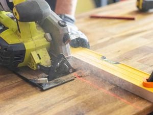 Close up of circular saw from a power tool kit cutting through timber with a laser line and spirit level.