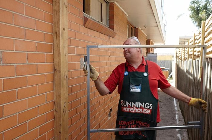 A person positioning a hinge on metal gate frame