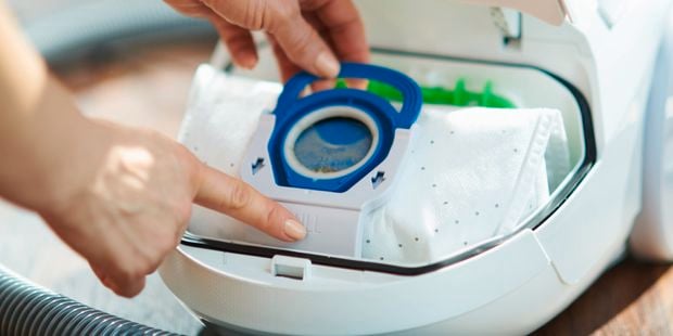 Close up of a person replacing the filter of a vacuum.