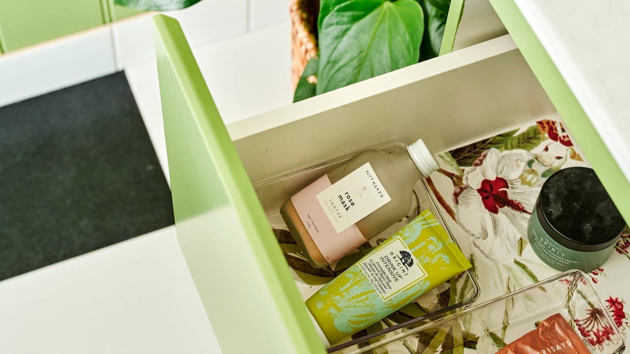 An open drawer in a green powder room.