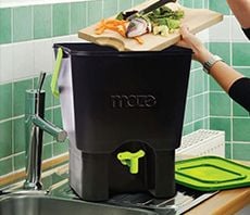 Person emptying food scraps into indoor compost bin