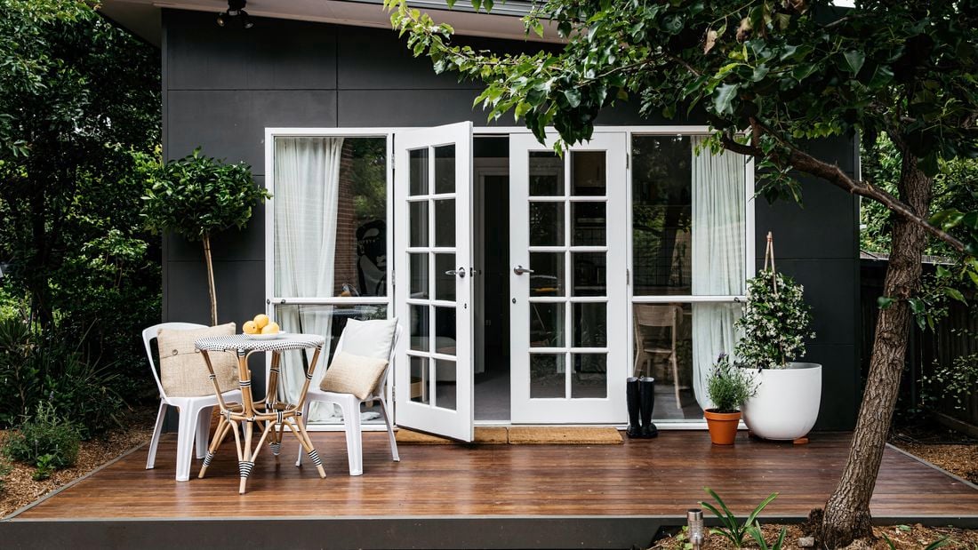 Granny flat with wooden porch with outdoor table/chairs set and plants