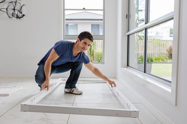 A tradesman about to affix a frame into a windowsill