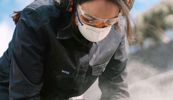 A lady with a face mask and ear muffs on.
