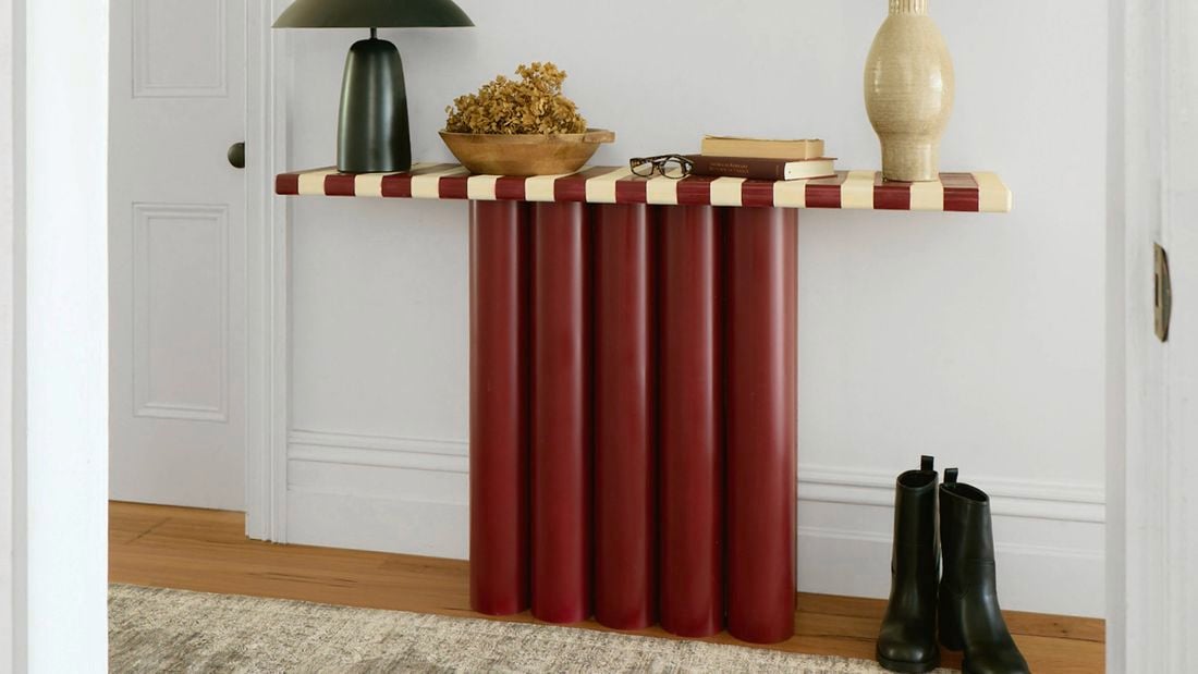 A completed hallway console table made from red cylindrical legs with a striped tabletop, styled with decor in a home interior.