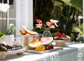An outdoor table with wooden cutting boards used as serving platters for fruit