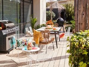 An outdoor entertaining area with a BBQ, dining table and chairs, and a decking.