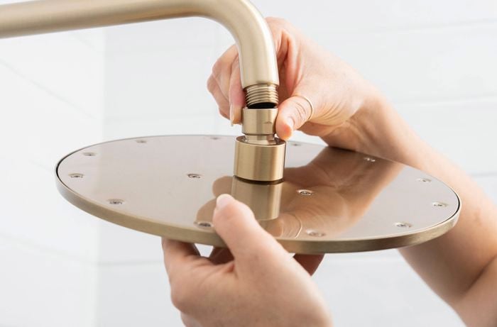 A person is is attaching a new shower head onto a shower arm to ensure correct alignment and avoid cross-threading during installation