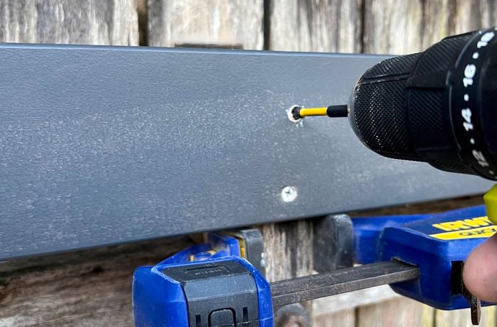 Ryobi power tool drilling into wooden panel that is attached to an outdoor fence