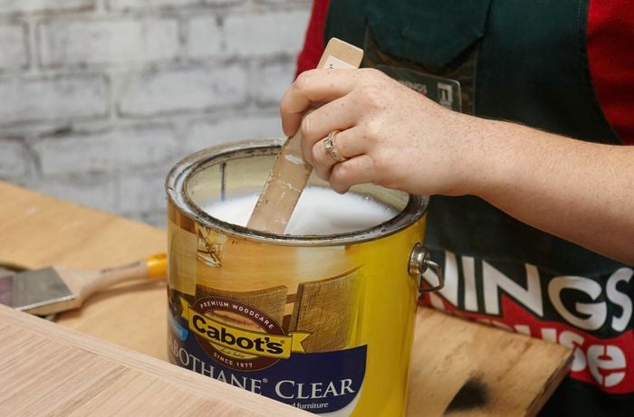 Person stirring tin of varnish.
