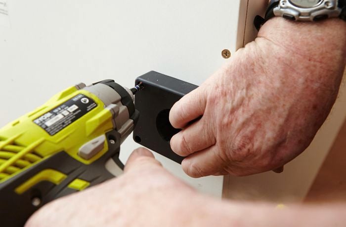 Person drilling screw into base panel of pantry