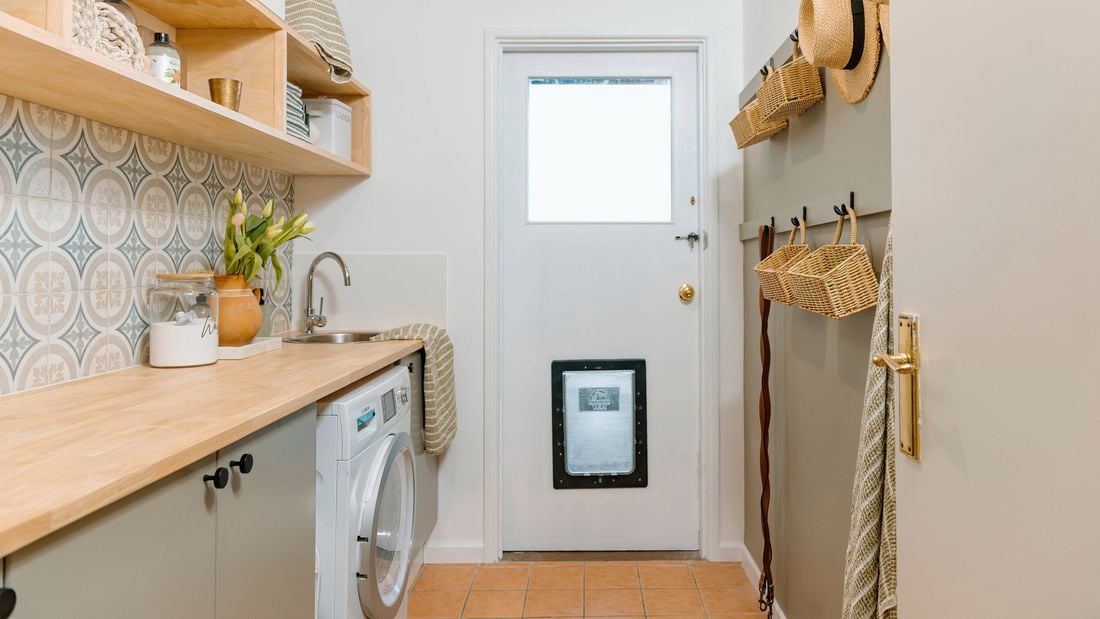 Updated laundry with doggy door, timber bench tops, timber shelving and mosica green and blue wall tiles