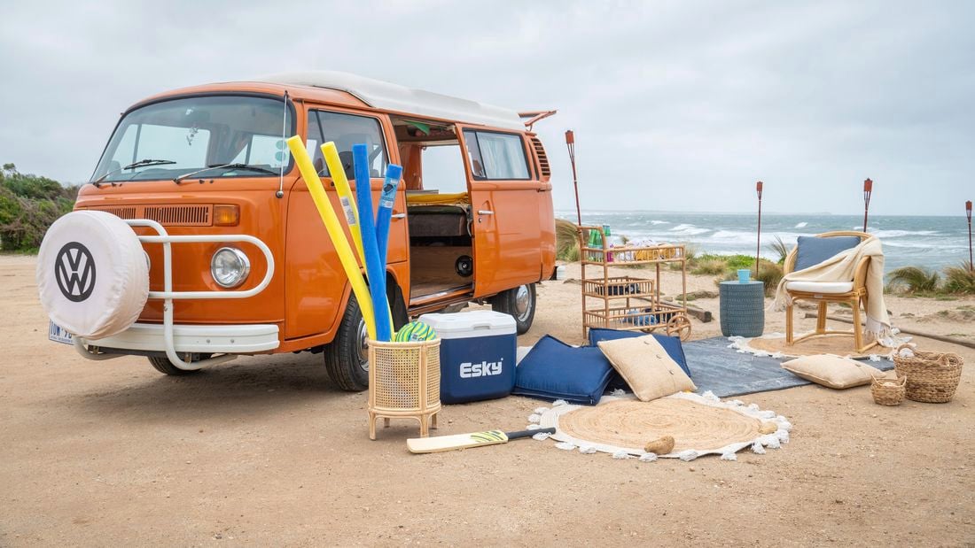 orange van at the beach with a picnic set set up