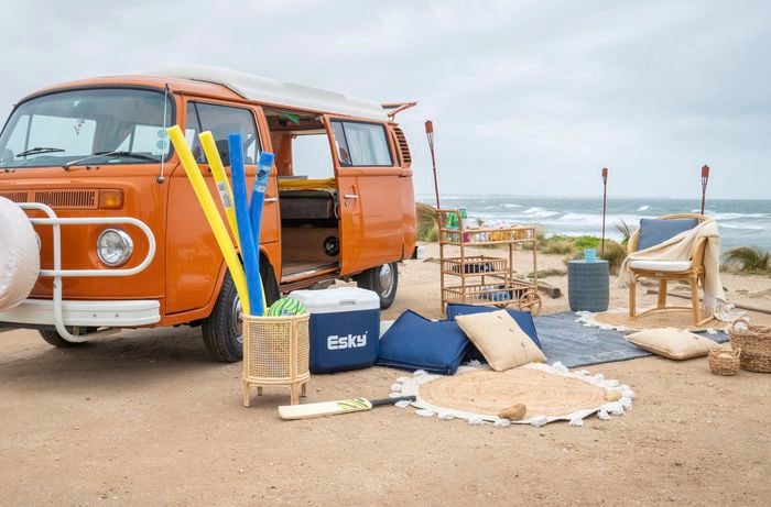 orange van at the beach with a picnic set set up