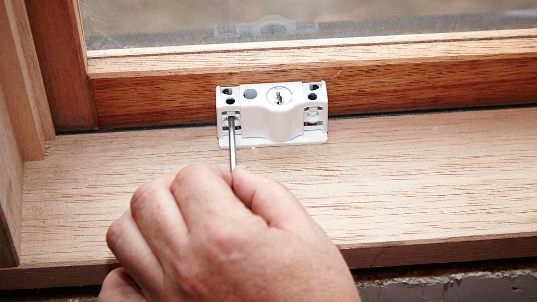 A person marking the position of screw holes for a lock using a nail