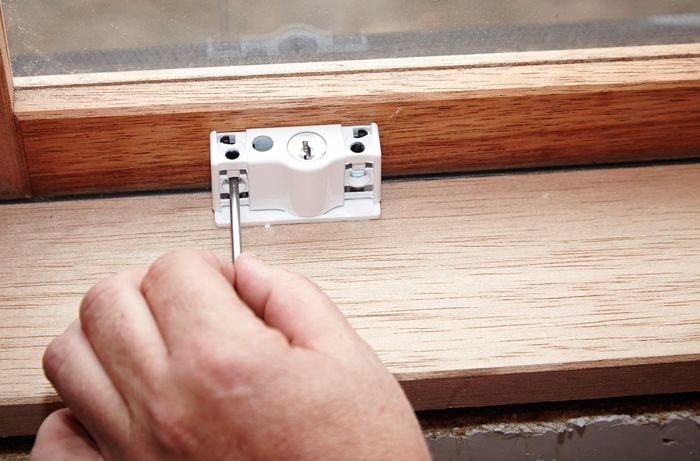 A person marking the position of screw holes for a lock using a nail