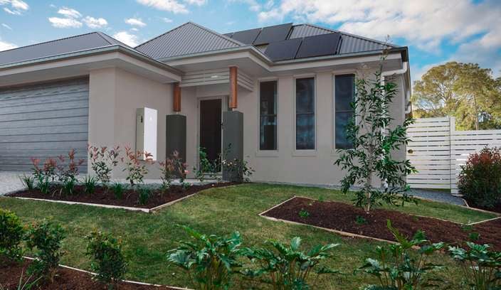 The exterior of a typical suburban home with a Tesla Powerwall installed alongside the garage wall.