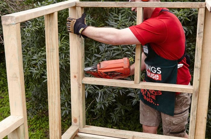 The back of the nesting box being attached to the rest of the chicken coop's wooden framework