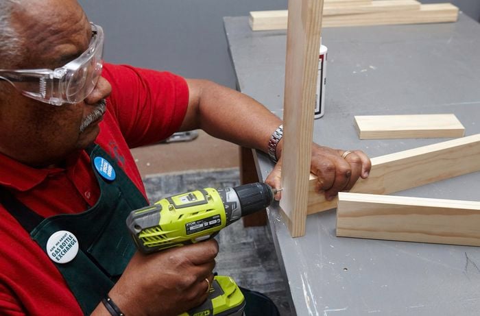 A person connecting two lengths of timber using a cordless driver