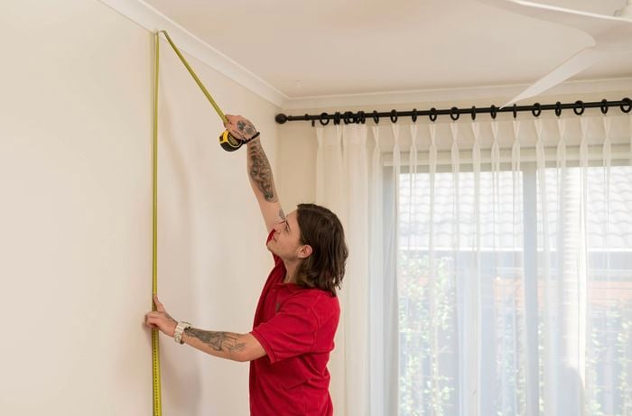 Measuring wall size with a tape measure.
