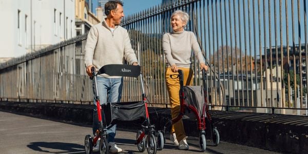 Two seniors are walking on the street with Altus walkers.