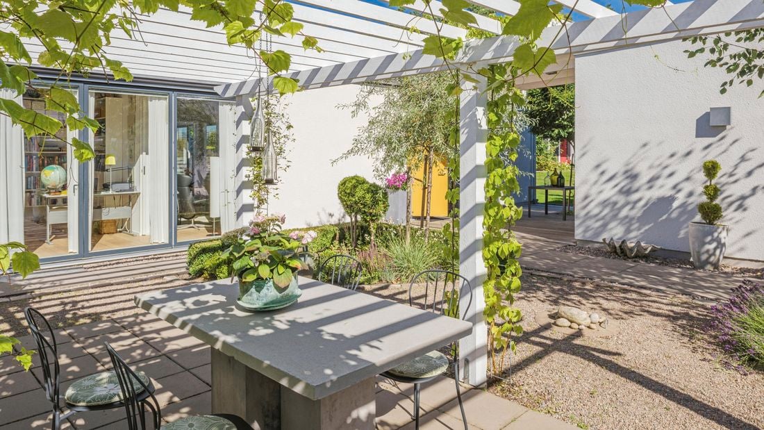 Outdoor pergola structure with hanging plants on it.