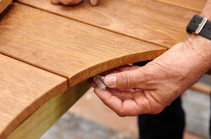 Person attaching butterfly cleat to part of a table where they have cut out a hole.