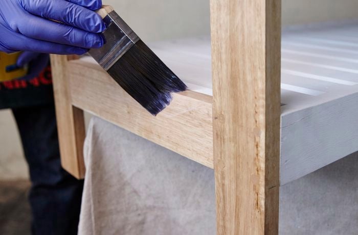 Person applying layer of varnish to shelving unit