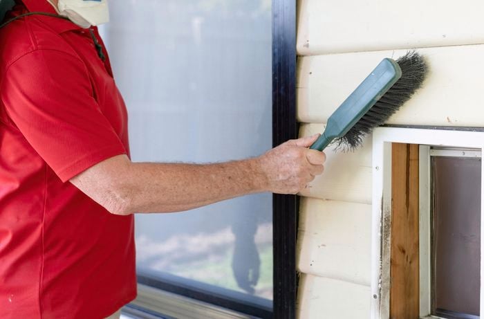 Person cleaning weatherboards with a small brush