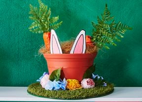 A Bunnings straw hat decorated with artificial turf, a plastic pot and faux carrots, flowers and bunny ears for Easter.