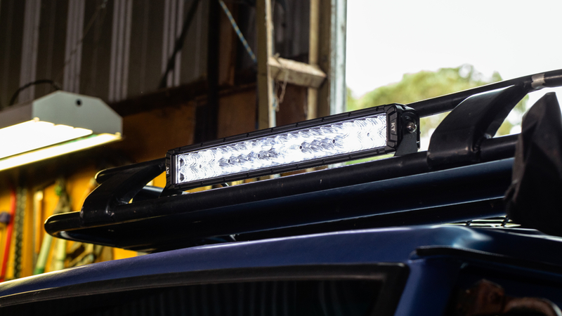 Illuminated KT 20'' Double Row LED light bar mounted to roof rack on 4WD vehicle.