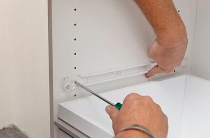 Screwing the drawer runners inside the cabinet.
